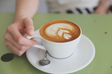 Cappuccino coffee with young woman hand