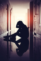 Silhouette of sad and depressed women sitting at walkway of condominium or office with backlit and lens flare,sad mood,feel tired, lonely and unhappy.