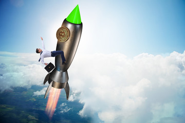 Naklejka na ściany i meble Businessman flying on rocket in bitcoin price rising concept