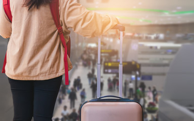 Young woman traveler standing and waiting after check in on gate with suitcase, Copy space