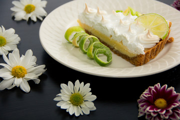 Lemon pie with lemon shell and flowers in black table