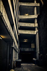 A dark and eerie Chicago city alley with an urban parking structure at night.