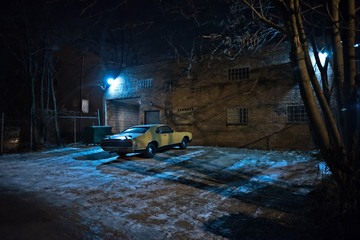 Vintage muscle car in a dark Chicago city urban alley on a winter night.