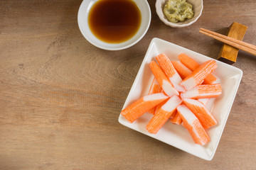 top view of crab sticks served with soy sauce and wasabi on wooden table. delicious food appetizer.