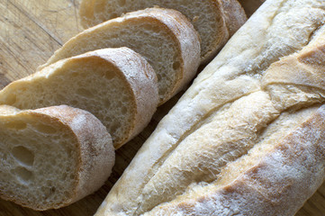A freshly sliced baguette on a wooden chopping board