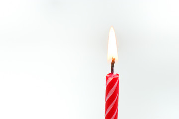 red birthday candle burning in front of white background