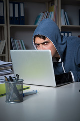 Young hacker hacking into computer at night