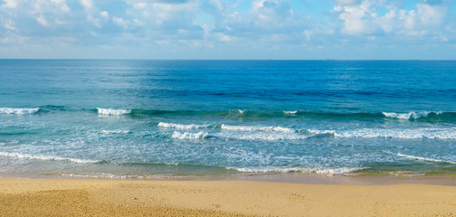 Deserted sandy beach of the Indian Ocean. In the blue sky cumulus clouds. Wide photo.