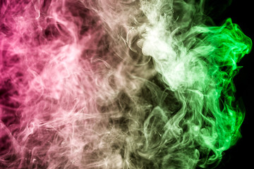 Thick colorful smoke of green and pink on a black isolated background. Background from the smoke of vape