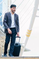 Business man walking at outdoors with luggage in the routine of working with determination and confidence. concept of business trip travel and transportation.