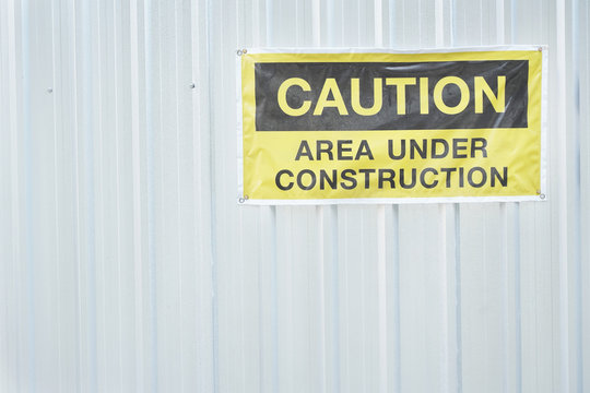 caution construction area sign on the metal wall