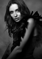 Black and white fashion portrait. Beautiful, sexy young woman in black. Professional makeup and hairstyle