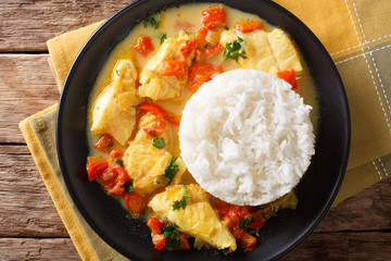 Stew fish with sauce of cilantro, onions, tomatoes, bell peppers and coconut milk with garnish of rice. horizontal top view