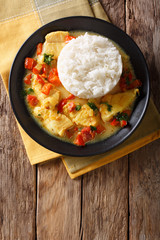 Pescado encocado or fish with coconut sauce is an Ecuadorian coastal dish close-up on a plate. Vertical top view