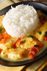 fish and rice with sauce of cilantro, onions, tomatoes, bell peppers and coconut milk close-up on a table. Vertical
