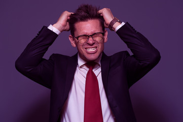 Stress, depression and insomnia - desperate young man manager or businessman tears his hair and screams with rage in purple tone