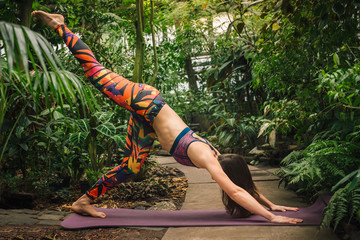 Attractive young caucasian woman doing yoga at botanical garden