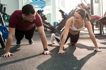 Obraz premium Portrait of cheerful sportive couple enjoying training in modern gym and smiling, looking at each other