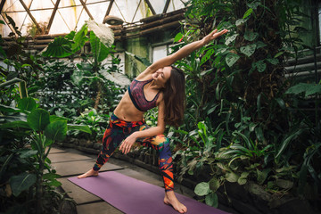 Naklejka na ściany i meble Young smiling caucasian woman doing yoga exercises at botanical garden