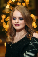 Smiling girl with beautiful makeup in front of christmas tree