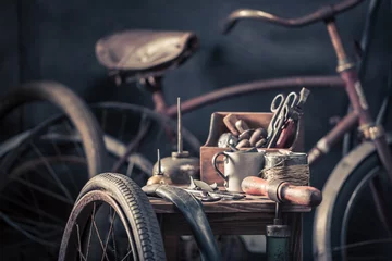 Crédence de cuisine en verre imprimé Vélo Old bicycle repair workshop with wheels, tools, and rubber patch