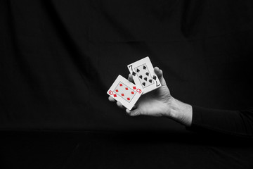 Man's hands with playing cards. Black background