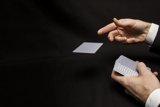 Man's hands with playing cards. Black background