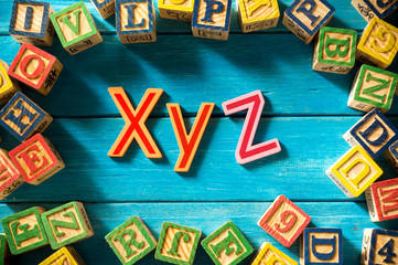 Close up arrangement of "XYZ" alphabet on blue background. Preschool, education concept or other your content. Long shadow and vignette effect.