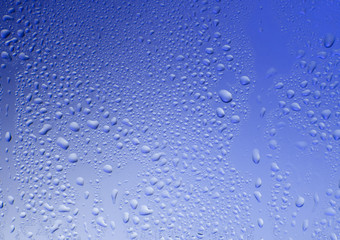 Glass blue texture with water drops on a blue background