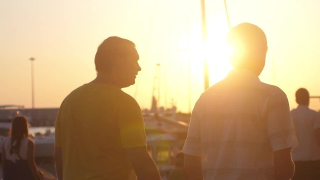 Two men are walking at the promenade. Beautiful sunset at the yachts beach. slow motion. 1920x1080