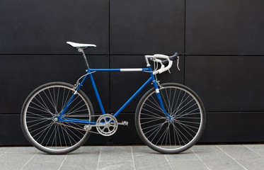 Vintage blue city bicycle against a black wall