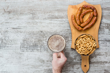 man's hand holds a beer mug near snacks. Top view. Space for text