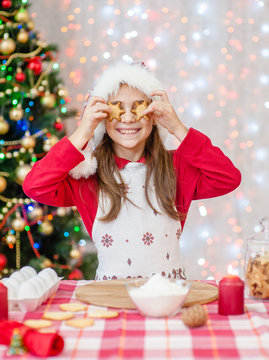 smiling girl having fun at home, holds cookie  before his eyes like in glasses