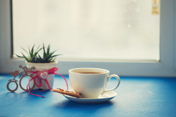Valentine's Day - cup of coffee with a cookies stands on a blue surface