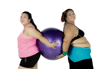 Fototapeta na wymiar Two fat women with fitness ball on studio