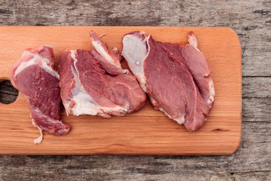 Raw pork meat on cutting board on a table. Top view