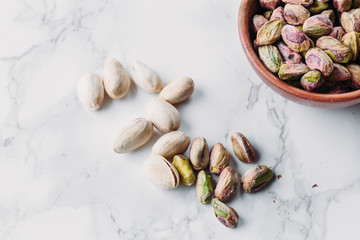 Pistachios in wooden bowl on marble background with copy space 