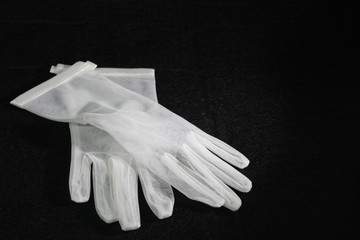 I guanti in pizzo bianco del matrimonio della sposa poggiati su sfondo nero