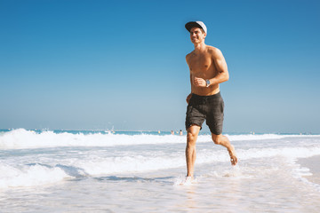  Shirtless young man enjoying jogging outside on the beach.