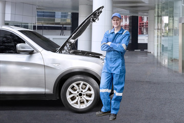 European mechanic standing near a broken car