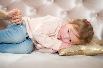 Charming little girl falls asleep on a pink sofa.