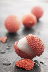 wet lychee in the foreground on slate
