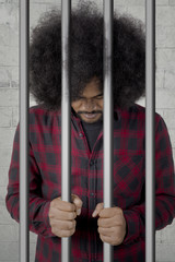 African prisoner standing behind bars
