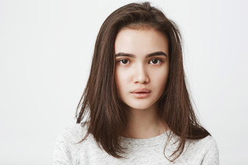 Close up studio shot of tired, exhausted young teenage girl, who is looking at camera with fed up look and half-opened mouth. Newcomer tired of listening customers complaints.