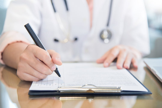 female doctor writing something on clipboard.