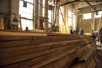 Stack of wooden blanks at the sawmill. Workers on background.