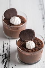 Chocolate mousse in a glasses on a white wood background.