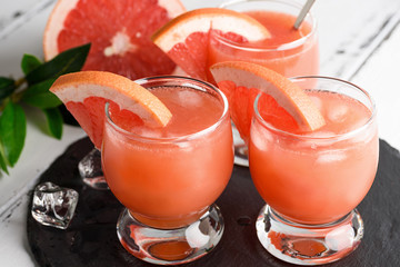 Grapefruit juice and ripe grapefruits on a wooden background