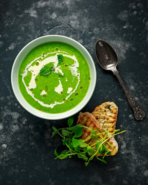 Green sweet pea and mint soup with cream and olive oil drizzle served with grilled ciabatta toasts