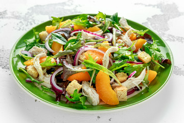 Fresh salad with chicken breast, peach, red onion, croutons and vegetables in a green plate. healthy food